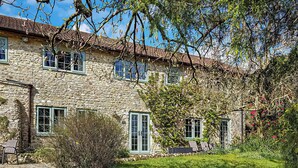 A stone building with multiple windows and a garden area with grass and shrubs. - 2 bedroom accommodation in Membury (Membury)