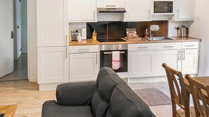 A modern kitchen with white cabinets, a black oven, and a microwave. - 2 bedroom accommodation in Membury (Membury)