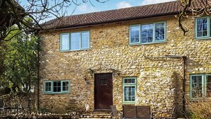 Un bâtiment en pierre avec un toit recouvert de tuiles, de nombreuses fenêtres et une porte d’entrée.