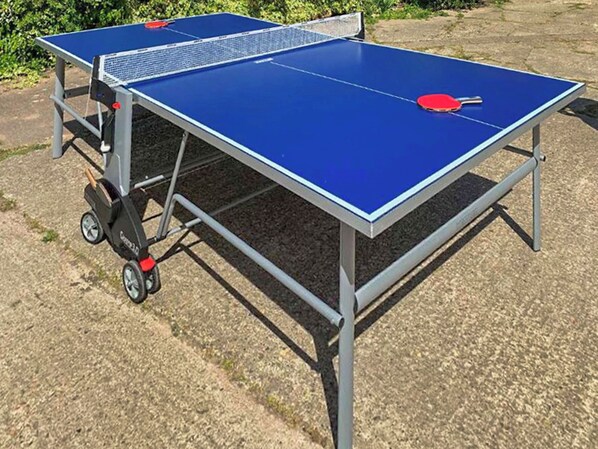 Una mesa de ping pong portátil con ruedas y una red, montada al aire libre.