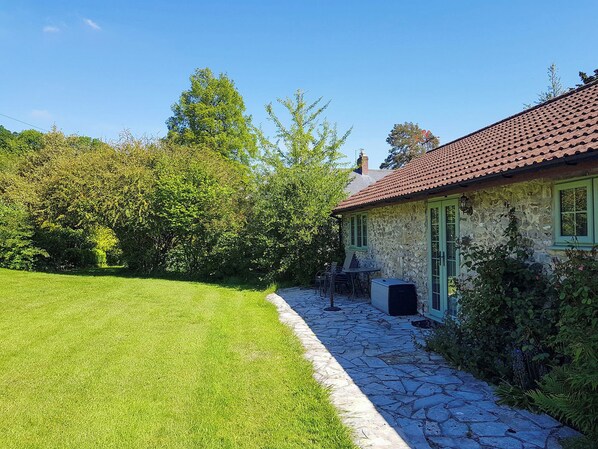 A stone house with a tiled roof, a stone pathway, and a well-maintained lawn.