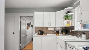 Une cuisine moderne avec des meubles blancs, un plan de travail, un évier et une cuisinière.
