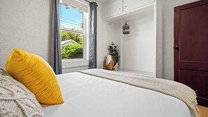 Une chambre à coucher avec un lit, une fenêtre avec des rideaux, une porte en bois et une lanterne suspendue.