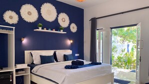 A modern bedroom with a white bed, blue walls, and decorative wall art. - Lovys Gili Air (Gili Air)