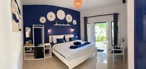 A modern bedroom with a large bed, a bedside table, a mirror, and decorative wall art. - Lovys Gili Air (Gili Air)