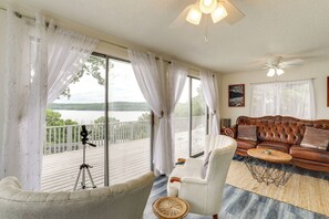 A room with a large window, a telescope, a leather sofa, and a wooden coffee table. - Norfork Lake Views: Home w/ Deck in Henderson (Henderson)