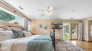 A bedroom with a bed, a ceiling fan, a window, and a door leading to a balcony. - The Rose Garden Estate with Swim Spa - an Irvie Home (Albuquerque)
