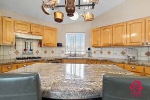 A kitchen with granite countertops, wooden cabinets, and a central island with seating.