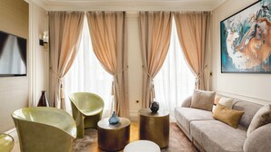 En moderne stue med en beige sofa, grønne stole og et rundt sofabord.
