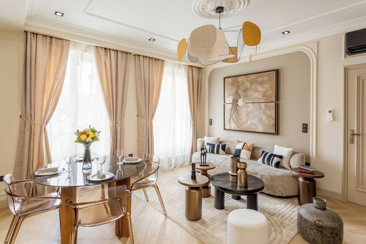 A modern living room with a dining area, featuring a round table, clear chairs, a sofa, and a coffee table.