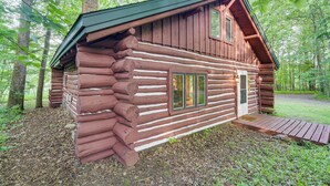 Une cabane en rondins avec une façade en bois, un porche et une cheminée.