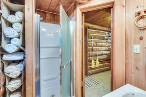 Interior de uma cabana de madeira com banheiro, porta-toalhas e parede de madeira.