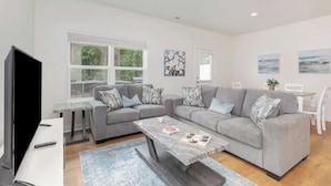 A modern living room with a grey sofa set, a coffee table, and a flat-screen TV.