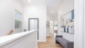A hallway with a reception desk, a bench, and a large abstract painting on the wall.