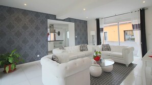 Una sala de estar moderna con un sofá blanco, una mesa de centro de vidrio y una alfombra estampada.