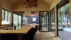 A modern kitchen with a large island, black chairs, and a view of a forest through large windows. - and FOREST Katsuura Takenohanare (Katsuura)