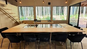 A modern kitchen with a large island, black chairs, and large windows overlooking a forest. - and FOREST Katsuura Takenohanare (Katsuura)