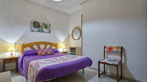 A bedroom with a bed, two bedside tables, a chair, and a wall clock. - Charming 2-bedroom apartment with WiFi, AC in fabulous Torrevieja (Torrevieja)