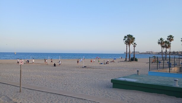 A sandy beach with palm trees, a volleyball net, and a lifeguard stand. - Charming 2-bedroom apartment with WiFi, AC in fabulous Torrevieja (Torrevieja)