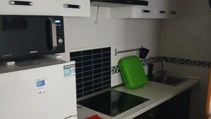 A compact kitchen with a microwave, a refrigerator, a sink, and a green cutting board. - Charming 2-bedroom apartment with WiFi, AC in fabulous Torrevieja (Torrevieja)