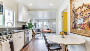 Una cocina moderna con armarios blancos, una estufa y un comedor con una mesa redonda y sillas.