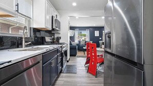A modern kitchen with stainless steel appliances, a dining area with red chairs, and a view of the outside.