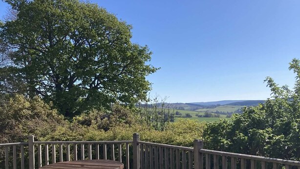 A wooden deck with picnic tables and a view of the countryside. - The Bothy -  a cottage that sleeps 4 guests  in 2 bedrooms (Lumphanan)