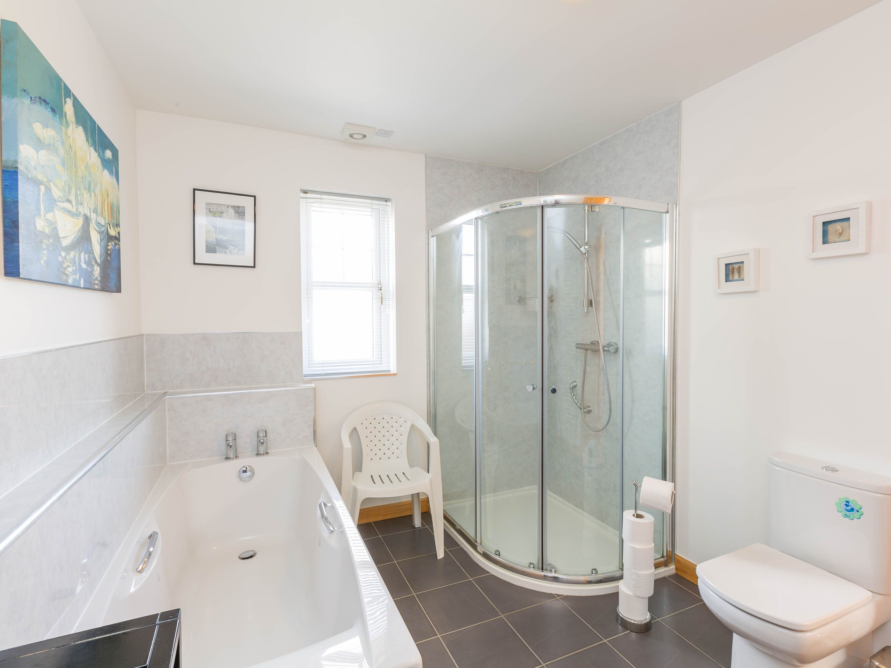 A modern bathroom with a glass-enclosed shower, a bathtub, and a toilet.