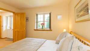A bedroom with a bed, a window with a view, a door, and a framed picture on the wall. - Broombank Cottage - sleeps 6 guests  in 3 bedrooms (Inverness)