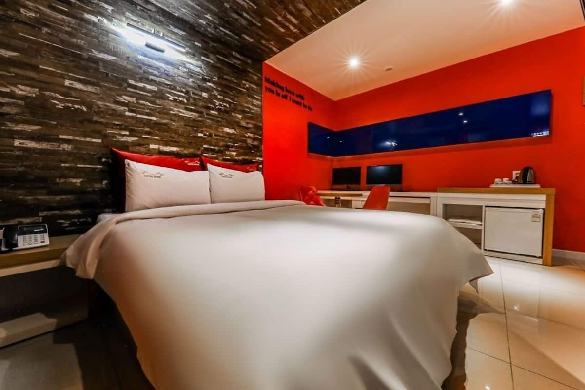 Una habitación de hotel moderna con una cama grande, un escritorio y un televisor.