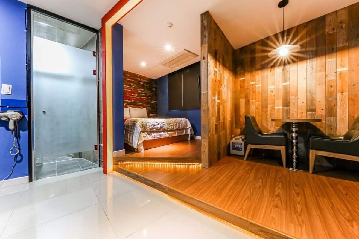 Habitación de hotel con cama, escritorio y silla. Pared de madera y pared azul.