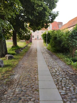 A cobblestone pathway leading to a building with a red roof. - Apartment 'Veronika' with Lake View, Private Terrace and Shared Garden (Wesenberg)