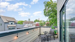 A rooftop terrace with a seating area, a view of the city skyline, and a large tree.