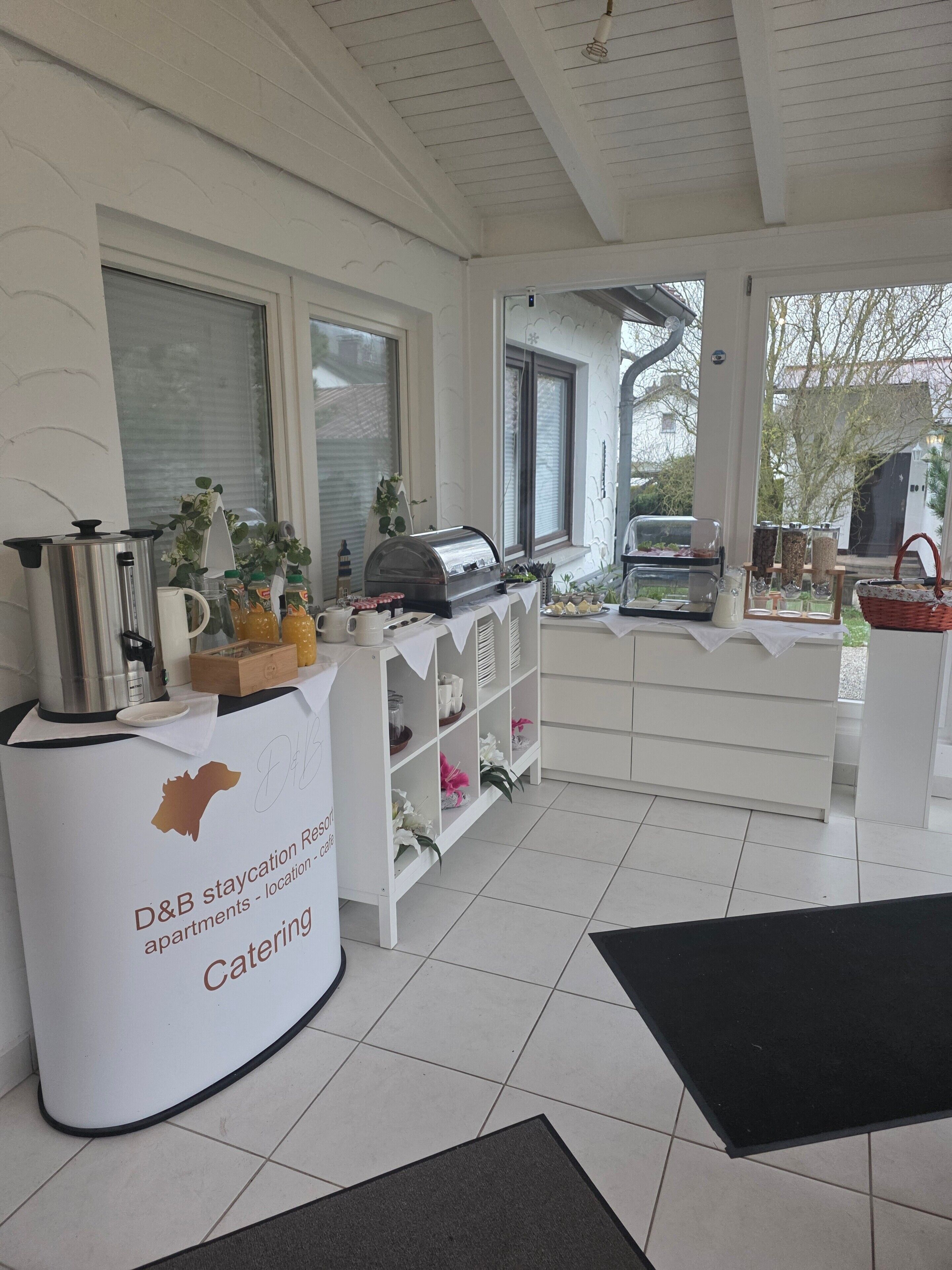 Un’area ristoro con una macchina per caffè, espositori di cibo e un cartello per il resort D&B staycation.