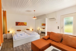 Una habitación de hotel moderna con cama, sofá, espejo y ventana con vistas.