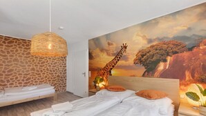 A bedroom with a giraffe mural, a wooden bed, a hanging light, and a nightstand with a plant. - Holiday Home 'Giraffe' with Private Terrace and Wi-Fi (Niedenstein)