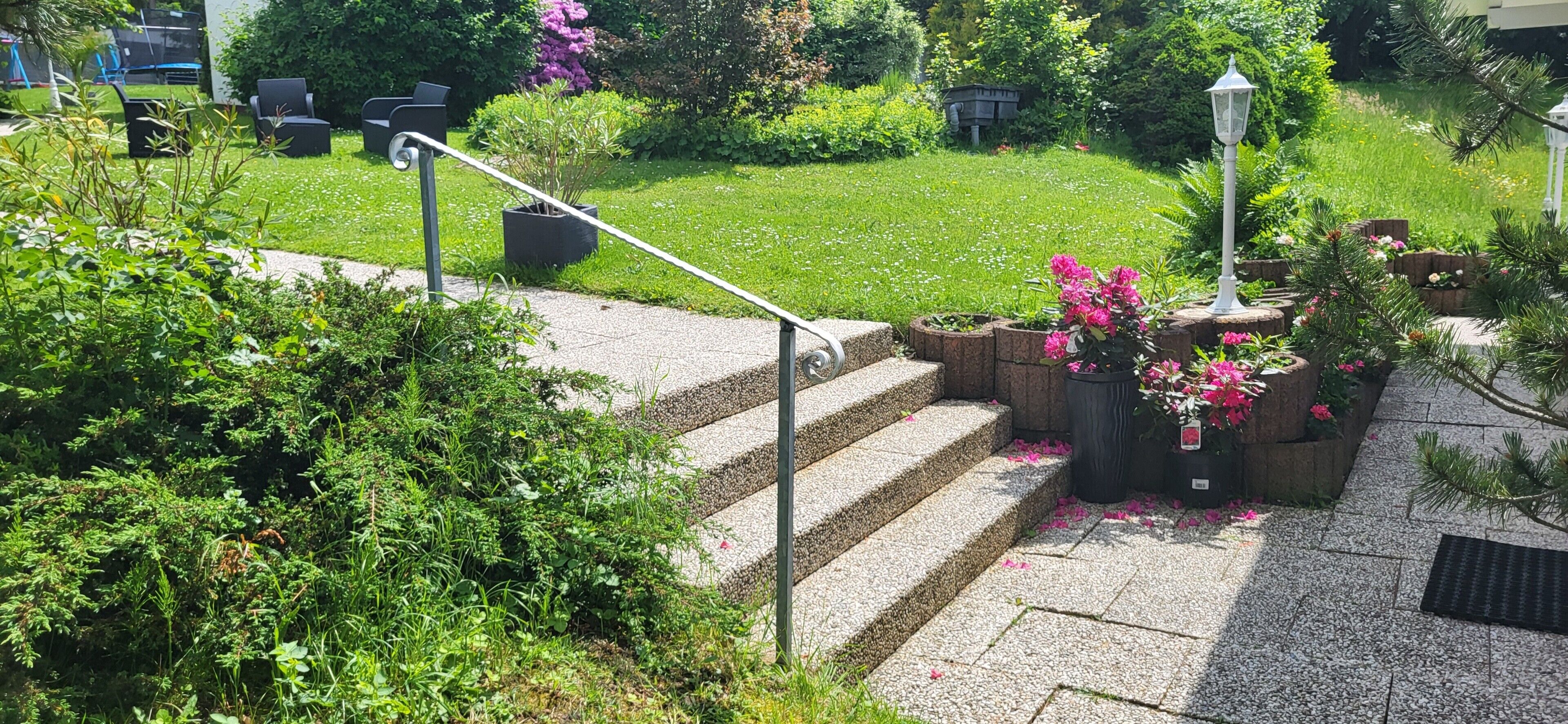 A garden with a stone staircase, outdoor seating, and potted plants.
