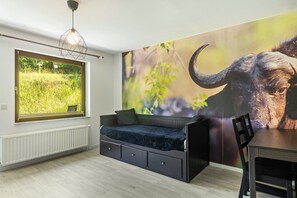 A room with a window, a sofa, a dining table, and a wall mural. - Holiday Home 'Büffel' with Private Terrace and Wi-Fi (Niedenstein)