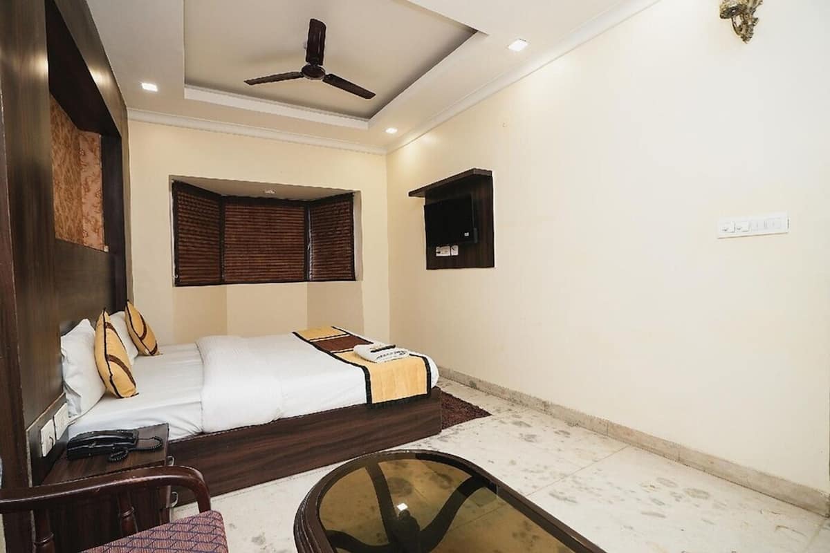 A bedroom with a bed, bedside table, chair, ceiling fan, and a small table with a glass top.