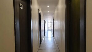 A long, narrow hallway with doors on both sides, leading to a bright room at the end.