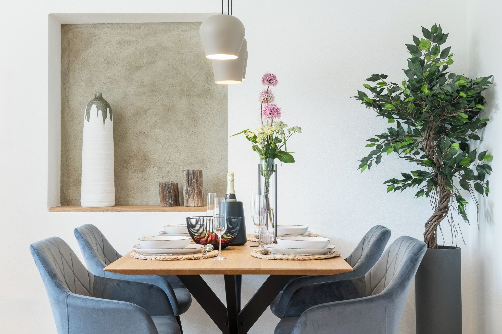 A dining table set with plates, glasses, and a centerpiece.