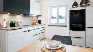 A modern kitchen with white cabinets, a wooden countertop, and a window with a view. - FENJOY vacation apartment No°9 with terrace | garden | BBQ (Bernau am Chiemsee)