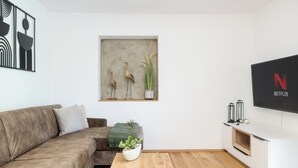 A modern living room with a brown sofa, a coffee table with a plant, a wall-mounted artwork, and a white entertainment unit with a Netflix logo. - FENJOY vacation apartment No°9 with terrace | garden | BBQ (Bernau am Chiemsee)
