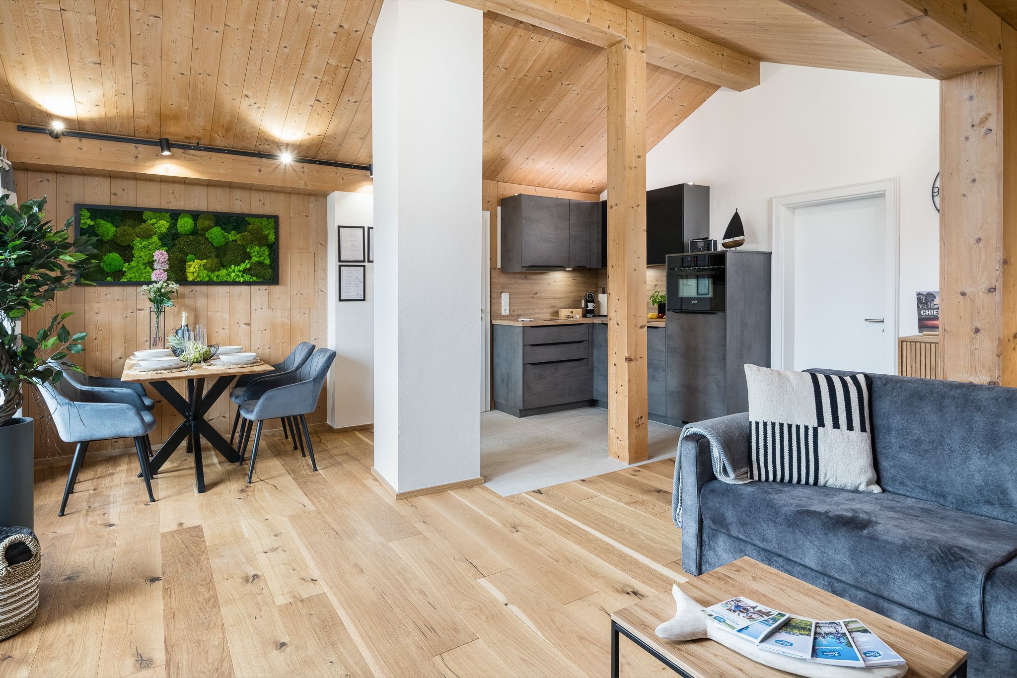 Un interior moderno con comedor, cocina y sala de estar, con pisos de madera y un ambiente acogedor.