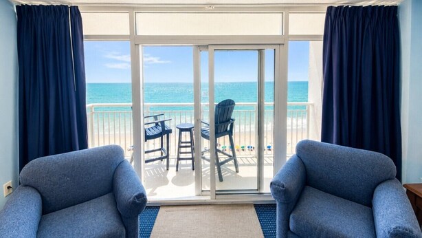 A balcony with two armchairs, a table, and chairs facing a beach. - Atlantic Lux. Spacious relax. (Myrtle Beach)