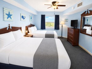Ein Hotelzimmer mit zwei Betten, einem Deckenventilator, einem Fernseher und Bildern an den Wänden.