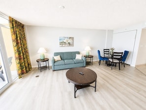 A living room with a sofa, coffee table, and chairs, a painting on the wall, and a window with curtains. - Vista Nuvia, Mins to Boardwalk (Myrtle Beach)