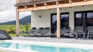A poolside area with lounge chairs and a wooden pergola.