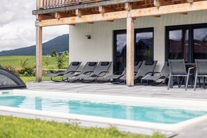 A poolside area with lounge chairs and a wooden pergola.