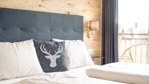 A bed with a grey headboard, white and grey pillows, and a white mattress.